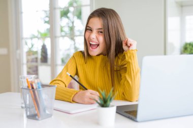 Güzel genç kız bilgisayar laptop kullanarak okuyor ve defter yazma gururlu ve kutlamak zafer ve başarı çok heyecanlı, tezahürat duygu
