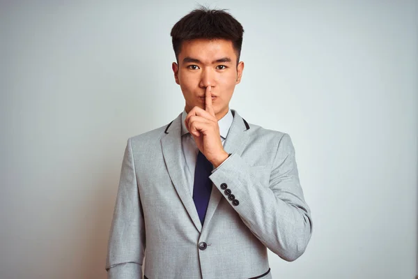 アジアの中国人ビジネスマンは スーツとネクタイを着て 孤立した黄色の背景の上に立って 唇に指で静かにするように頼みます 沈黙と秘密の概念 — ストック写真