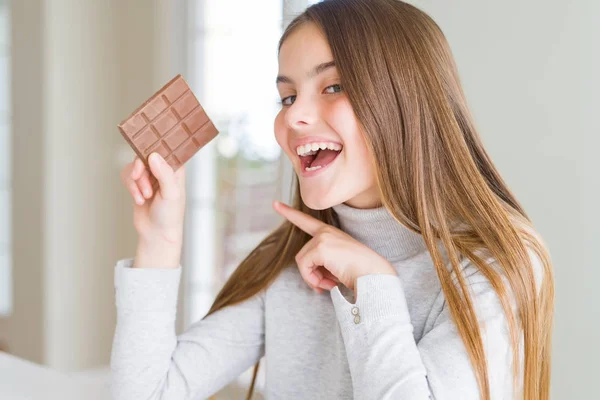 手と指で指し示すチョコレートバーを食べる美しい若い女の子の子供 — ストック写真