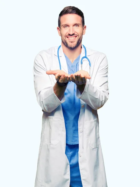 英俊的医生在孤立的背景穿医疗制服微笑与手手掌一起接受或给手势 保持和保护 — 图库照片