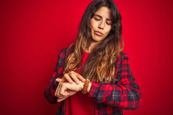 Young beautiful woman wearing casual jacket standing over red isolated background laughing at you, pointing finger to the camera with hand over body, shame expression