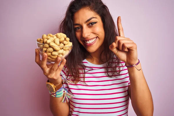 Jovem Bela Mulher Segurando Tigela Com Amendoins Sobre Fundo Rosa — Fotografia de Stock