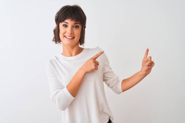 Genç güzel kadın rahat t-shirt izole beyaz arka plan üzerinde gülümseyerek ayakta giyen ve yan iki el ve parmakları ile işaret kamera bakarak.