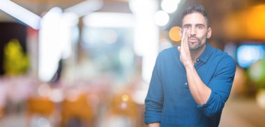 Yakışıklı delikanlı izole arka plan üzerinde el gizli söylenti söylüyor Ağızdan kötü amaçlı konuşma konuşma fısıldayan