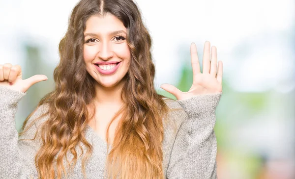 Gösterilen ve parmak altıncı ile gülümseyen ise kendinden emin ve mutlu yukarıyı kış elbise giyen genç güzel kadın.