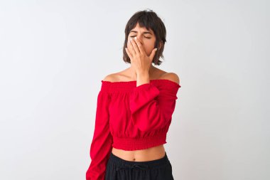 Izole beyaz arka plan üzerinde duran kırmızı yaz t-shirt giyen genç güzel kadın el ile ağız kapsayan yorgun esneme sıkılmış. Huzursuz ve uykululuk.