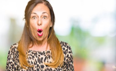 Leopar hayvan baskı elbisesi giyen güzel orta yaş kadın sürpriz ifade, korku ve heyecanlı yüz ile korkuyor ve şok.