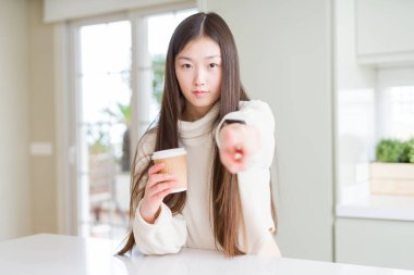Bir kahve içme güzel Asyalı kadın kamera ve size, el işareti, önde pozitif ve emin jest parmak ile işaret eden bir kağıt fincan almak