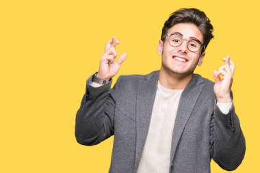 Umut ve gözleri kapalı geçiş parmaklarıyla gülümseyen izole arka plan üzerinde gözlük takan genç iş adamı. Şans ve batıl kavramı.