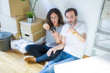 Orta yaş Senior çift kamera ve size, el işareti, ön, pozitif ve emin jest parmak ile işaret Smartphone kullanarak yeni bir eve hareket