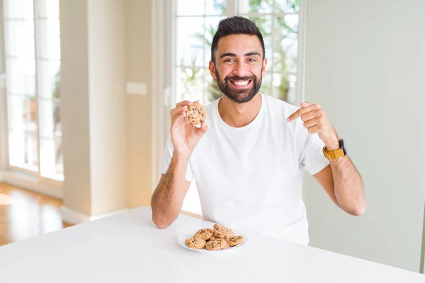 Όμορφος Ισπανικός Άνθρωπος Που Τρώει Τσιπς Σοκολάτας Μπισκότα Πρόσωπο Έκπληξη — Φωτογραφία Αρχείου