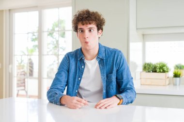 Evde rahat denim ceket giyen genç yakışıklı adam dudakları ile balık yüzü yapma, çılgın ve komik jest. Komik ifade.