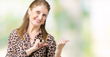 Üzerinde leopar elbise giyen güzel orta yaş olgun zengin kadın izole arka plan emin gülümseyen arkasından el ve kadar başparmak ile işaret