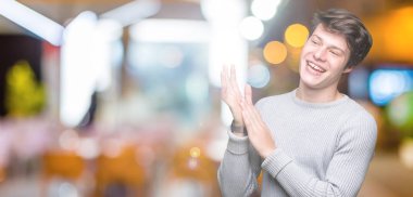 Genç yakışıklı adam giyen kış kazak izole üzerinde arka plan Clapping ve mutlu ve neşeli, gururlu gülümseyen birlikte eller alkış