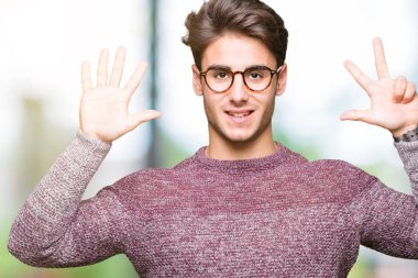 Gösterilen arka plan üzerinde gözlük takan genç yakışıklı adam izole ve parmakları ile işaret kendinden emin ve mutlu gülümseyerek süre 8 numaralı.