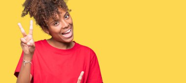 Güzel genç Afro-Amerikan kadın parmaklarını zafer işareti yaparken gösterilen kamera seyir gülümseyen izole arka plan yüzünden. İki numaralı.