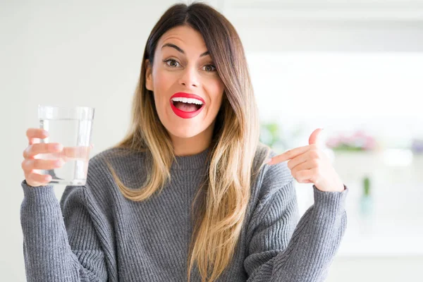 Young Beautiful Woman Drinking Glass Water Home Surprise Face Pointing — Stock Photo, Image