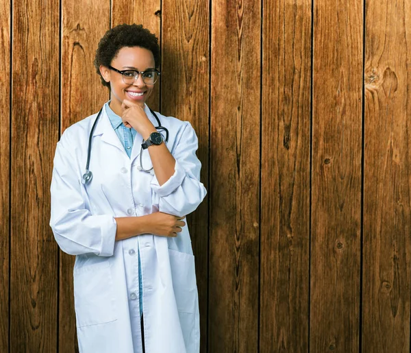 年轻的非洲裔美国医生妇女穿着医疗外套在孤立的背景看起来自信的镜头与交叉的手臂和手抬起下巴 积极的思考 — 图库照片