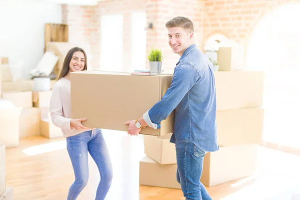 Belo jovem casal sorrindo no amor segurando um grande papelão b — Fotografia de Stock