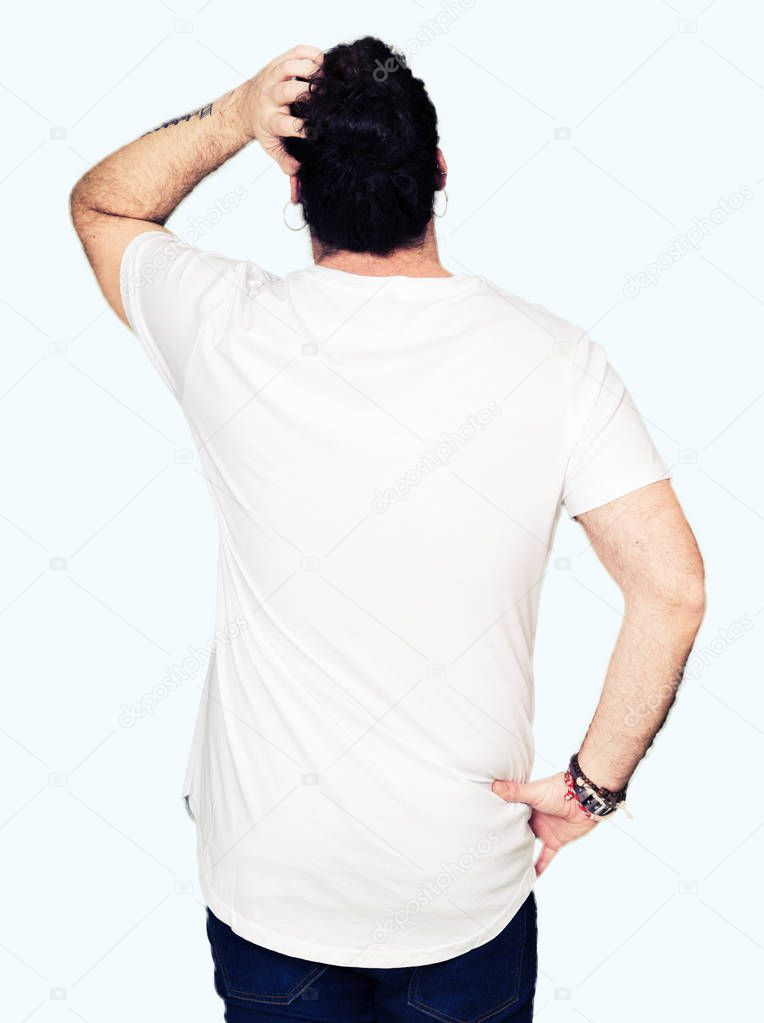 Young hipster man with long hair and beard wearing casual white t-shirt Backwards thinking about doubt with hand on head