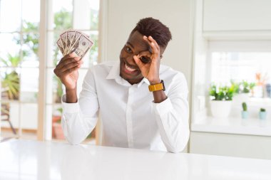 Mutlu yüzü ile elli dolar banka banknotları tutan Afro-amerikan adam parmakları ile bakarak göz el iyle ok işareti yapıyor gülümseyerek