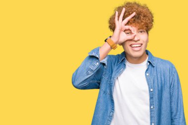 Gülümseyen, parmakları ile mutlu yüz üzerinden seyir göz el ile ok jest yapıyor kot ceket giyen afro saçlı Genç yakışıklı adam.