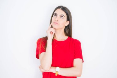 Genç güzel kadın soru hakkında düşünme çene üzerinde el ile beyaz izole arka plan üzerinde rahat kırmızı t-shirt giyen, dalgın ifade. Düşünceli bir yüzle gülümsüyor. Şüphe kavramı.