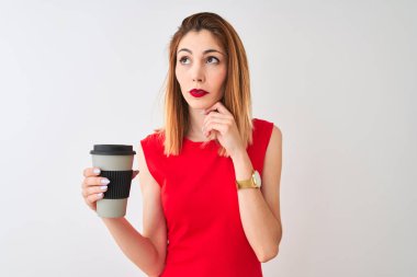 Genç güzel kızıl saçlı kadın içme izole beyaz arka plan ciddi yüz soru hakkında düşünme üzerinde kahve götürmek, çok karışık bir fikir