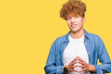 Afro saçlı kot giyen genç yakışıklı adam ceket el ele tutusun ve rahat ve neşeli gülümseyen parmak çarpı işareti. Başarı ve iyimser