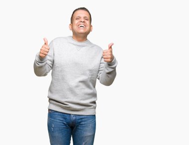 Orta yaş Arap adamın el ile pozitif jest yapıyor izole arka plan başarı işareti üzerinde spor kazak giydiğini başparmak gülümseyen ve mutlu. Neşeli bir ifadeyle, kazanan jest kameraya bakıyor.