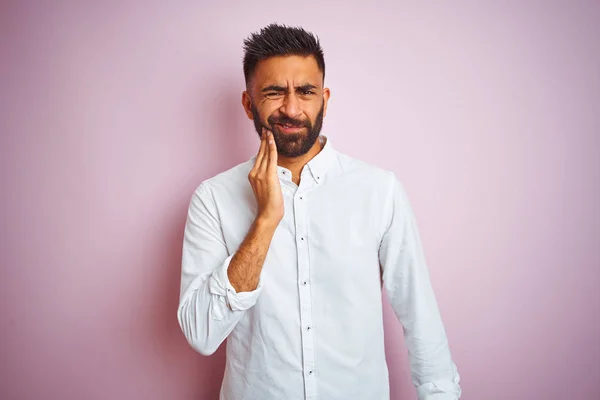 Young indian businessman wearing elegant shirt standing over isolated pink background touching mouth with hand with painful expression because of toothache or dental illness on teeth. Dentist concept.