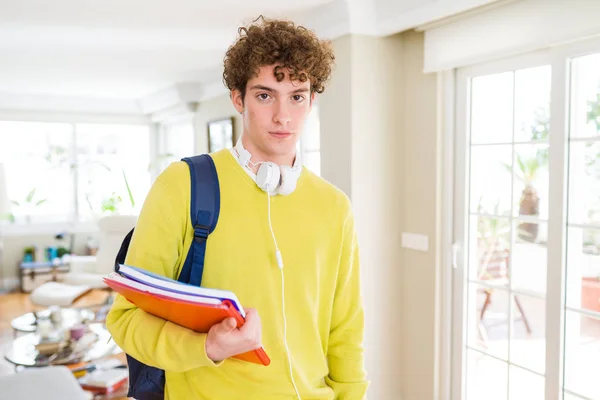 年轻的学生男子戴着耳机和背包拿着笔记本与自信的表情在聪明的脸思考认真 — 图库照片