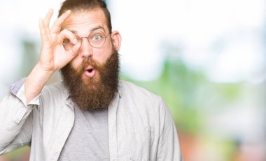 Gözlük takan genç sarışın adam ok jesti yaparak şaşkın yüzüyle şoke oldu, göz lerinden parmaklarından bakıyor. İnanmayan ifade.