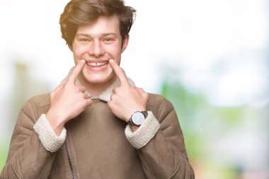 Genç yakışıklı adam giyen kış ceket izole üzerinde arka plan gülen açık ağız ile parmak işaret ve neşeli gülümseme zorlamadan