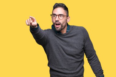 Yakışıklı delikanlı üzerinde gözlük takan izole arka plan ile sürpriz devam parmakla, açık ağız hayret ifadesi, önünde bir şey