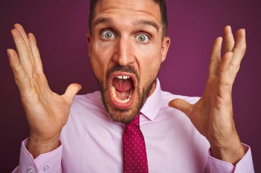 Mor izole arka plan üzerinde zarif gömlek ve kravat giyen iş adamı yakın deli kutluyor ve kollarını kaldırdı ve açık gözleri heyecan çığlık ile başarı için hayran. Kazanan kavramı