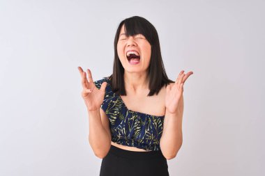 Genç güzel Çinli kadın izole beyaz arka plan üzerinde yaz çiçek t-shirt giyen kollarını kaldırdı ve kapalı gözleri heyecan çığlık ile başarı için deli ve deli kutluyor. Kazanan kavramı