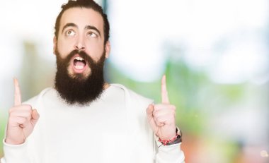 Uzun saç ve sakal sportif sweatshirt giyen genç adamla hayret ve yukarıya bakıp parmakları ile işaret şaşırttı ve silah kaldırdı.