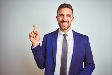 Yüzünde büyük bir gülümseme ile beyaz izole arka plan üzerinde genç yakışıklı iş adamı, kameraya bakarak yan el ve parmak ile işaret.