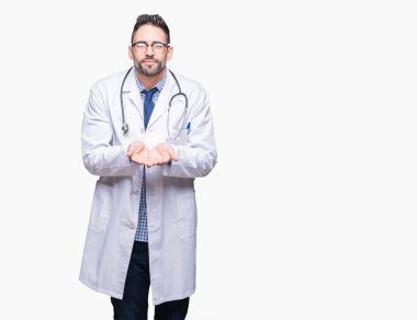 Izole arka plan üzerinde Yakışıklı genç doktor adam birlikte alma veya jest veren avuç içi ile gülümseyerek. Tutma ve koruma