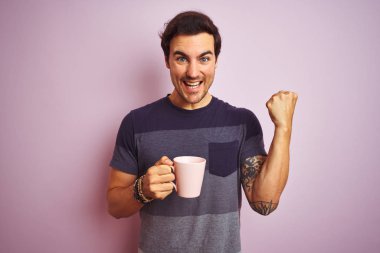 Izole pembe arka plan üzerinde kahve dövme içme fincan genç yakışıklı adam gurur çığlık ve zafer ve başarı çok heyecanlı kutluyor, duygu tezahürat