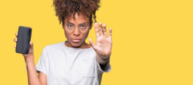 Smartphone ekran açık eliyle dur işareti ile ciddi ve kendine güvenen ifade, savunma jest yapıyor izole arka plan üzerinde gösterilen genç Afro-Amerikan kadın