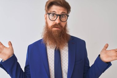 Genç kızıl İrlandalı işadamı takım elbise ve gözlük giyen izole beyaz arka plan habersiz ve kolları ve elleri ile karışık ifade kaldırdı. Şüphe kavramı.