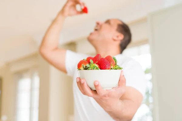 Middle age man eating strawberry at home