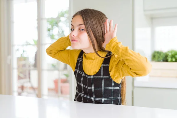年轻漂亮的金发女孩穿着休闲黄色毛衣在家里试图听到双手在耳朵上的手势 好奇的八卦 听力问题 — 图库照片
