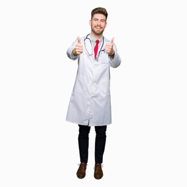 Genç yakışıklı adam tıbbi ceket giyen onaylama el ile pozitif jest yapıyor gülümseyen ve başarı için mutlu yaşasın doktor. Kamera, kazanan jest arıyorsunuz.