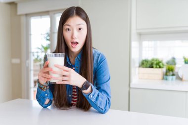 Güzel Asyalı kadın sürpriz bir yüz ile şok korkmuş süt taze bir bardak içme, korku ifade korku ve heyecanlı