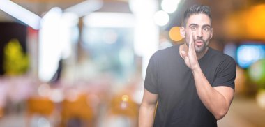 Yakışıklı delikanlı izole arka plan üzerinde el gizli söylenti söylüyor Ağızdan kötü amaçlı konuşma konuşma fısıldayan