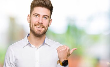 Seyir ve başparmak yanında yukarıyı mutlu yüz ile gülümseyen genç yakışıklı iş adamı.