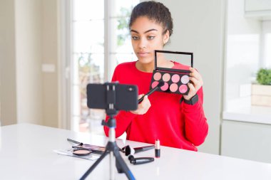 Genç afro-amerikan influencer kadın kayıt ciddi düşünme akıllı yüz kendine güvenen bir ifade ile öğretici makyaj